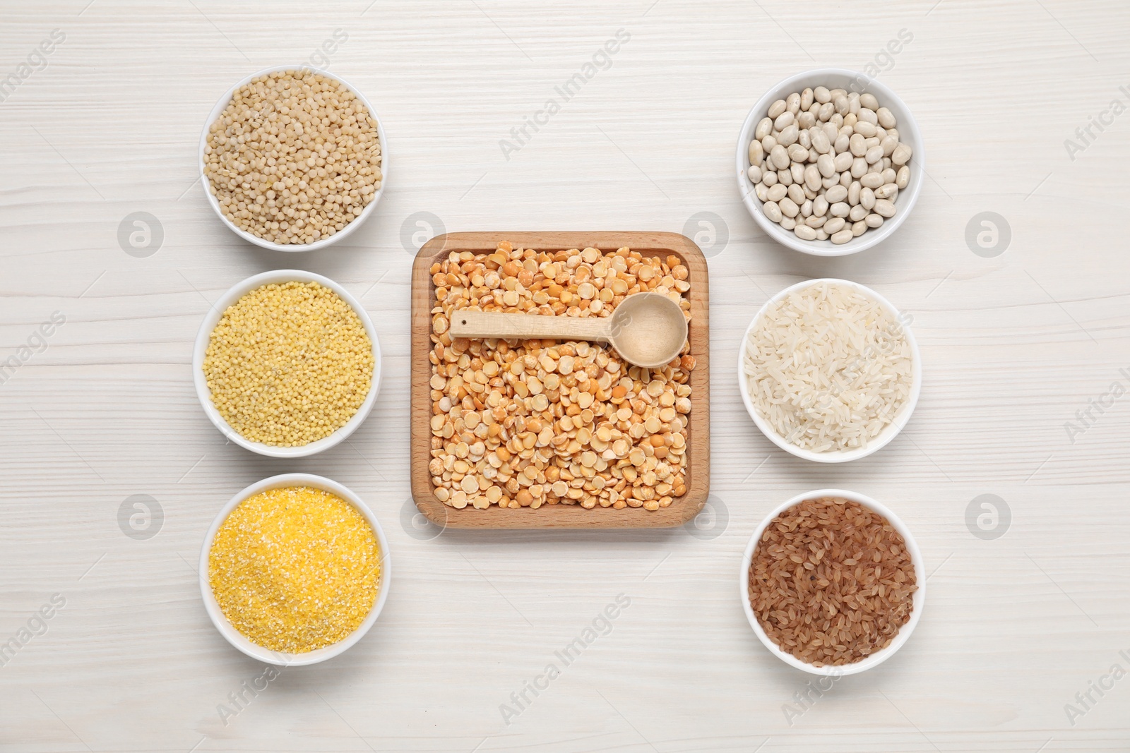 Photo of Different types of cereals and legumes on white wooden table, flat lay