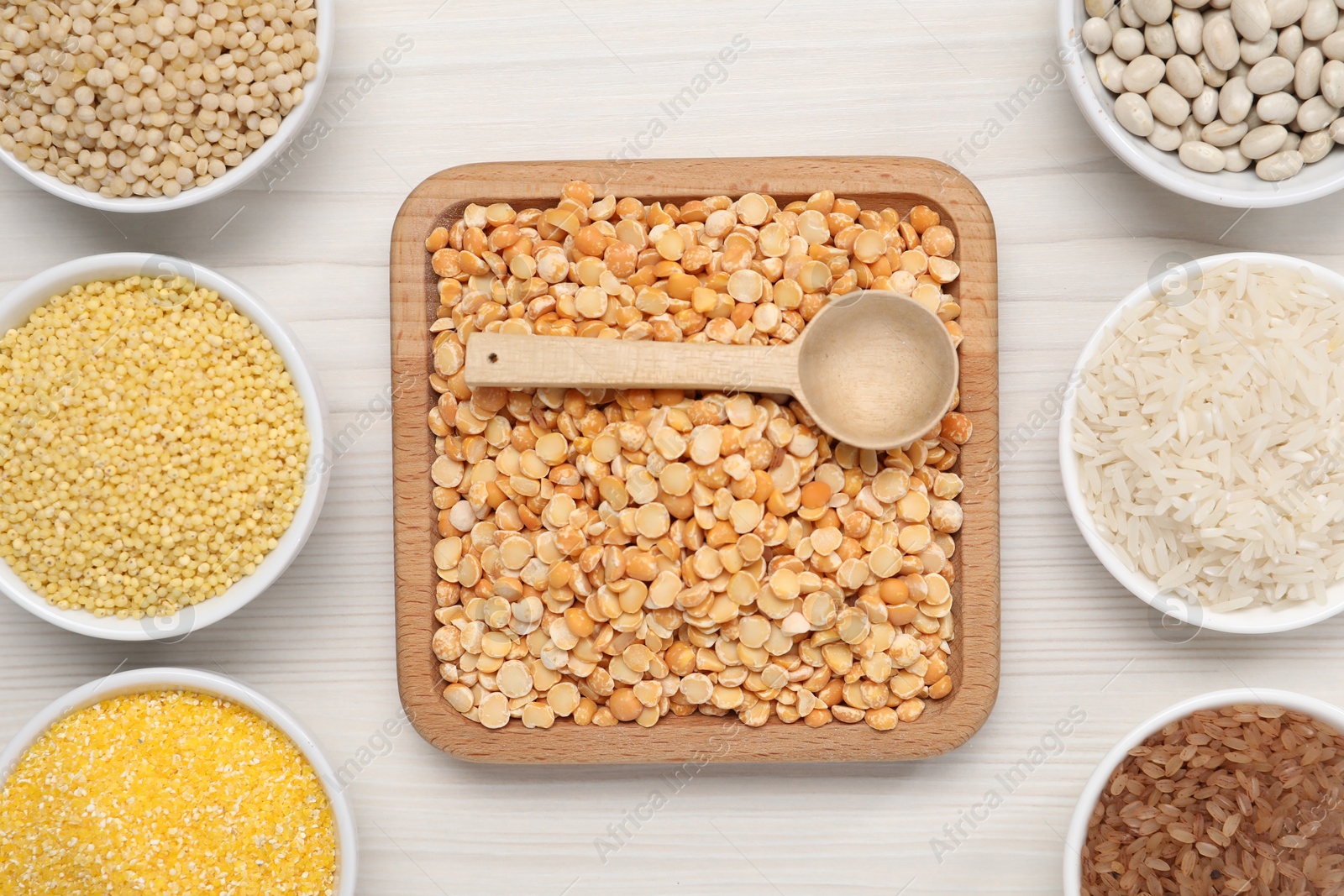 Photo of Different types of cereals and legumes on white wooden table, flat lay