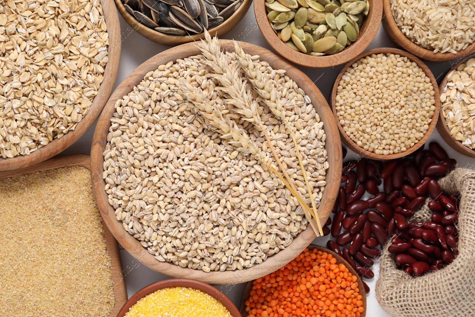 Photo of Different types of cereals, legumes and seeds on grey table, flat lay