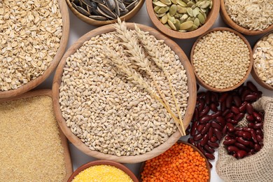 Photo of Different types of cereals, legumes and seeds on grey table, flat lay