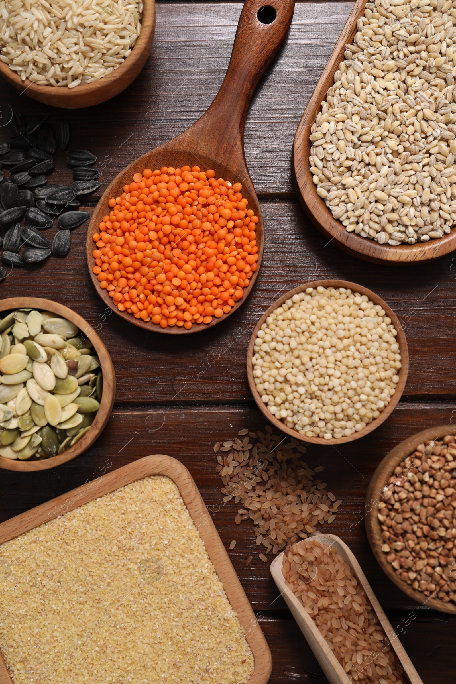 Photo of Different types of cereals, seeds and legumes on wooden table, flat lay