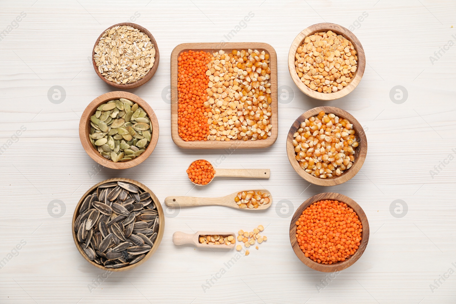 Photo of Different types of cereals, seeds and legumes on white wooden table, flat lay