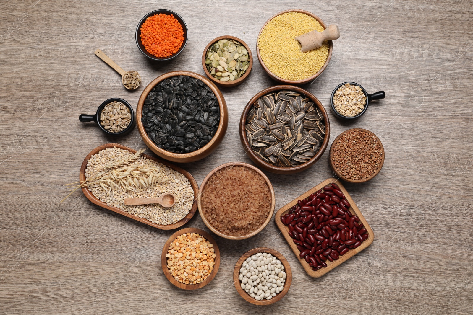 Photo of Different types of cereals, seeds and legumes on wooden table, flat lay