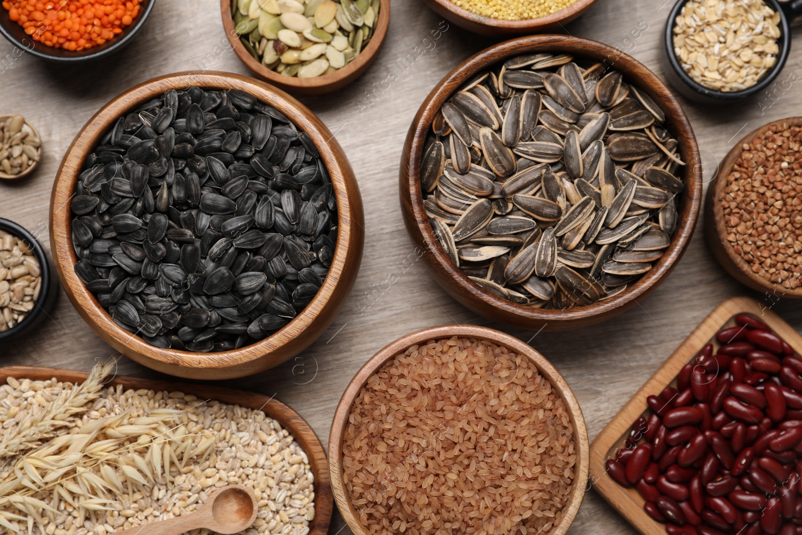 Photo of Different types of cereals, seeds and legumes on wooden table, flat lay