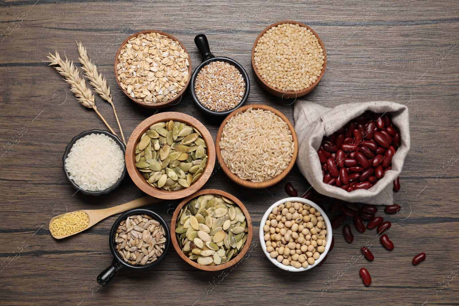 Photo of Different types of cereals, seeds and legumes on wooden table, flat lay