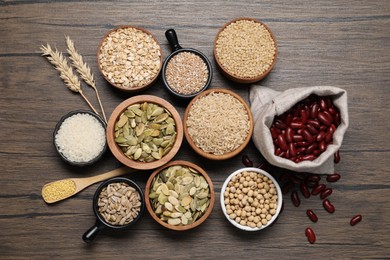 Different types of cereals, seeds and legumes on wooden table, flat lay