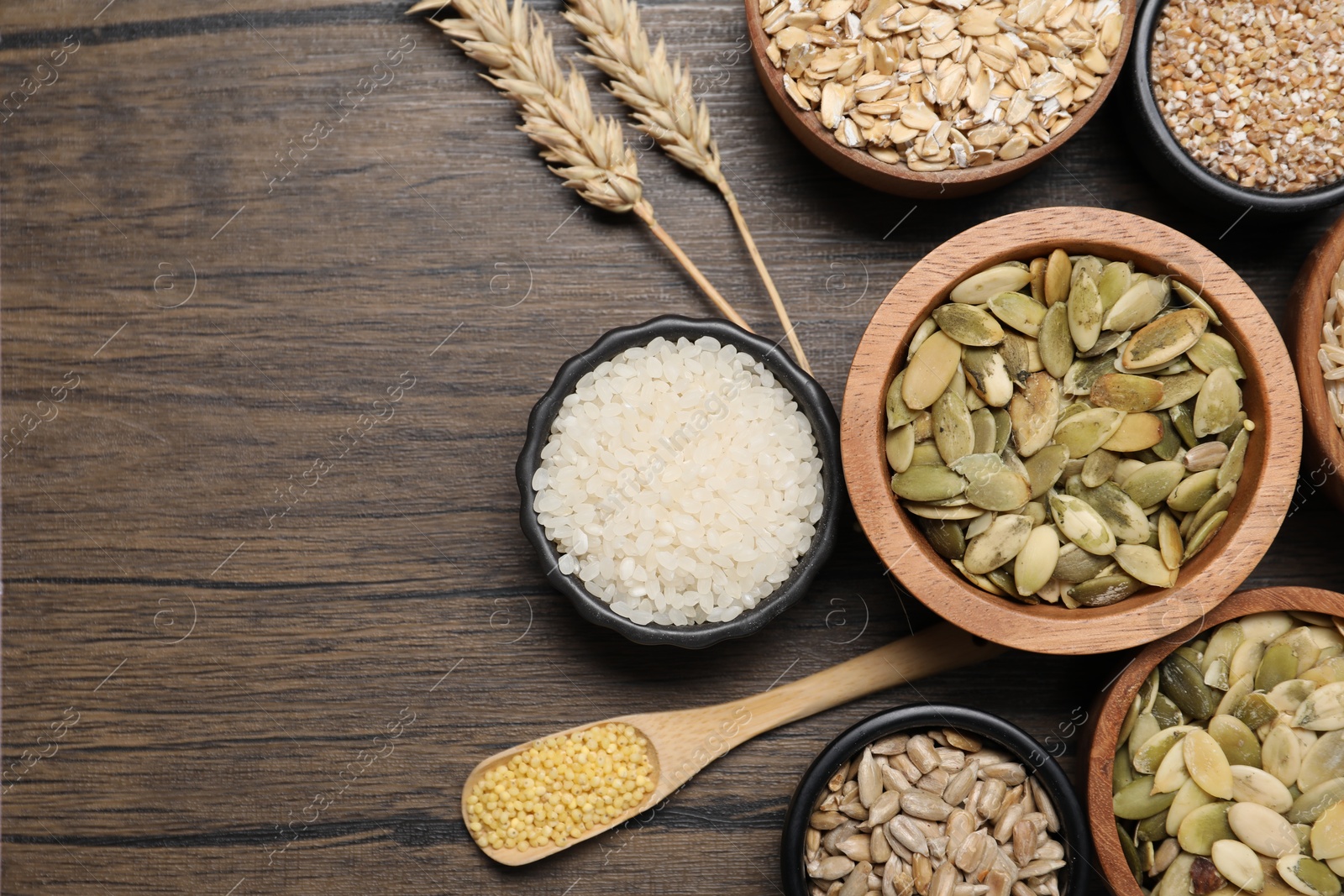 Photo of Different types of cereals and seeds on wooden table, flat lay. Space for text