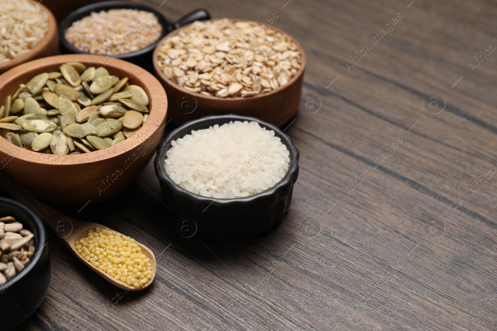 Photo of Different types of cereals and seeds on wooden table. Space for text