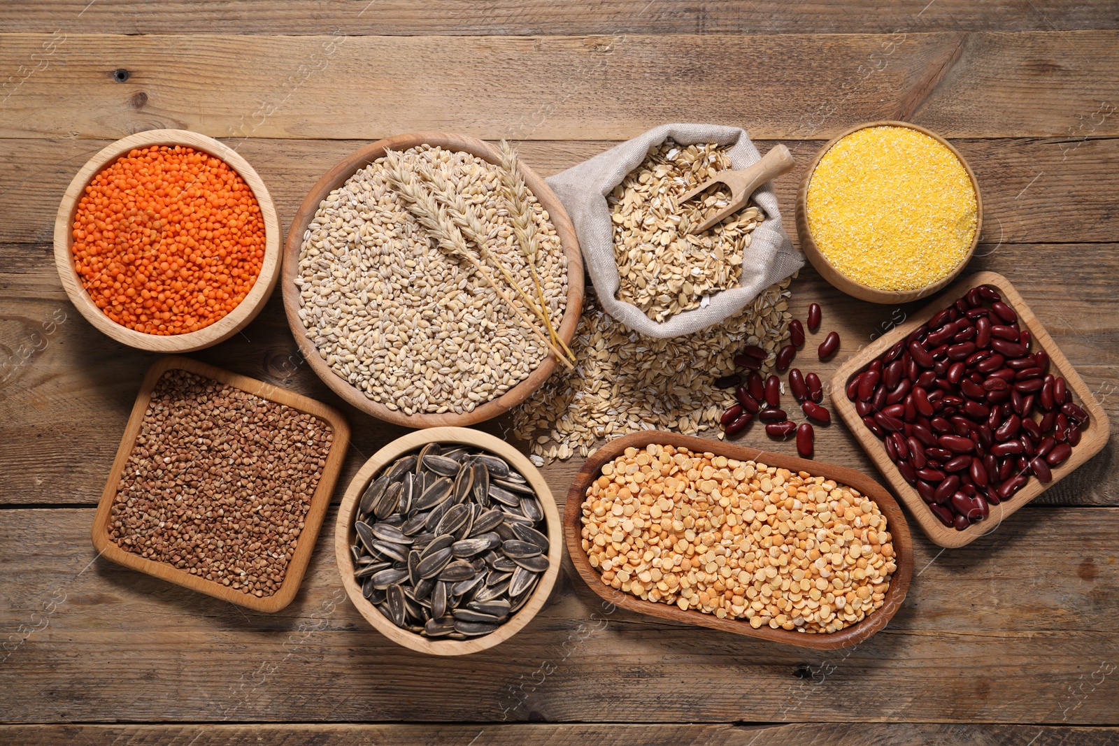 Photo of Different types of cereals, seeds and legumes on wooden table, flat lay