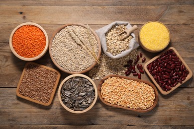 Different types of cereals, seeds and legumes on wooden table, flat lay