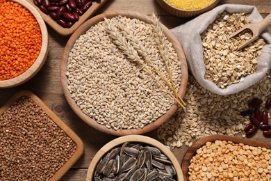 Photo of Different types of cereals, seeds and legumes on wooden table, flat lay