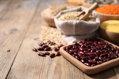 Photo of Different types of cereals and legumes on wooden table, closeup. Space for text