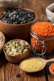 Different types of cereals, seeds and legumes on wooden table, closeup