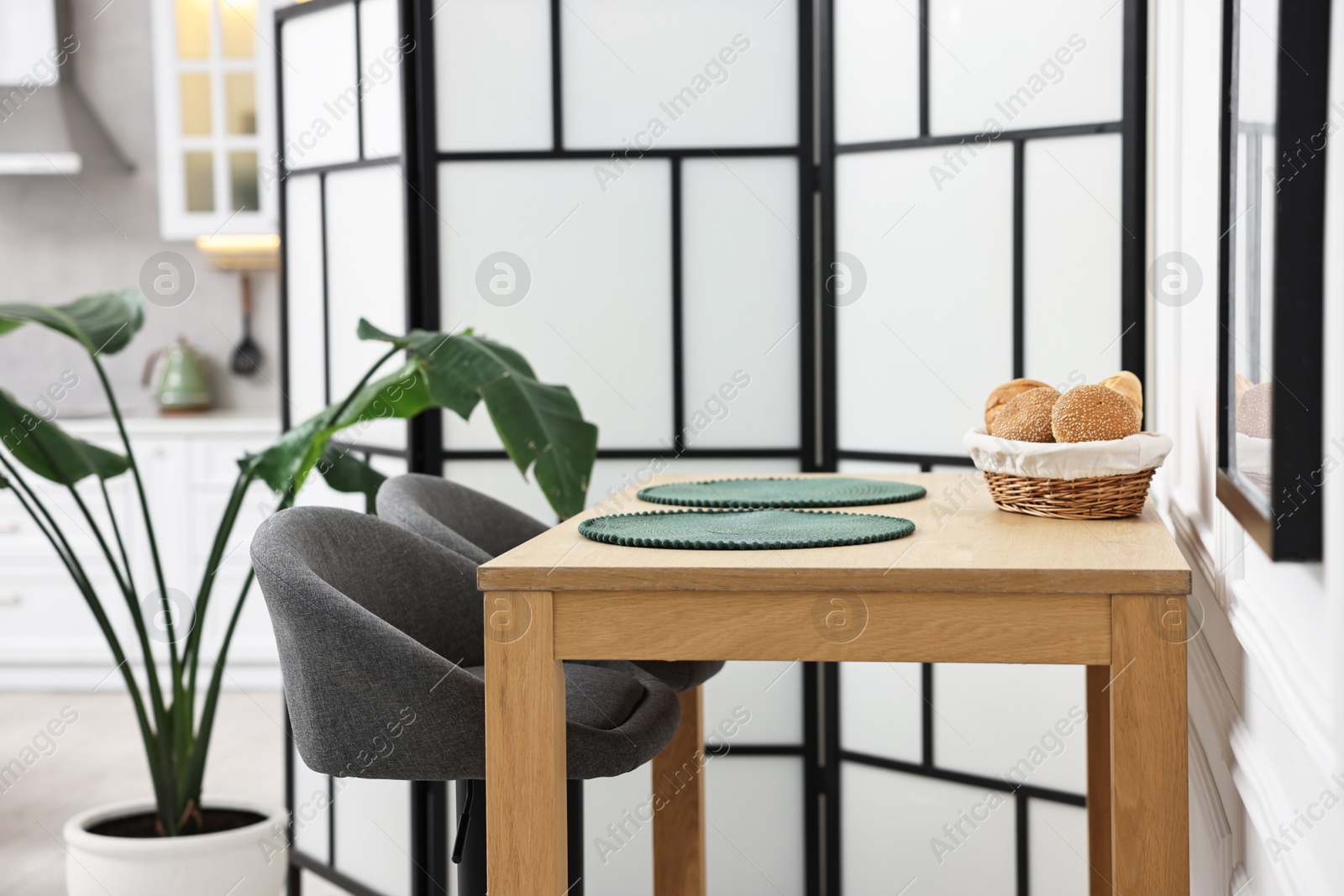 Photo of Stylish stools, houseplant and table near folding screen indoors