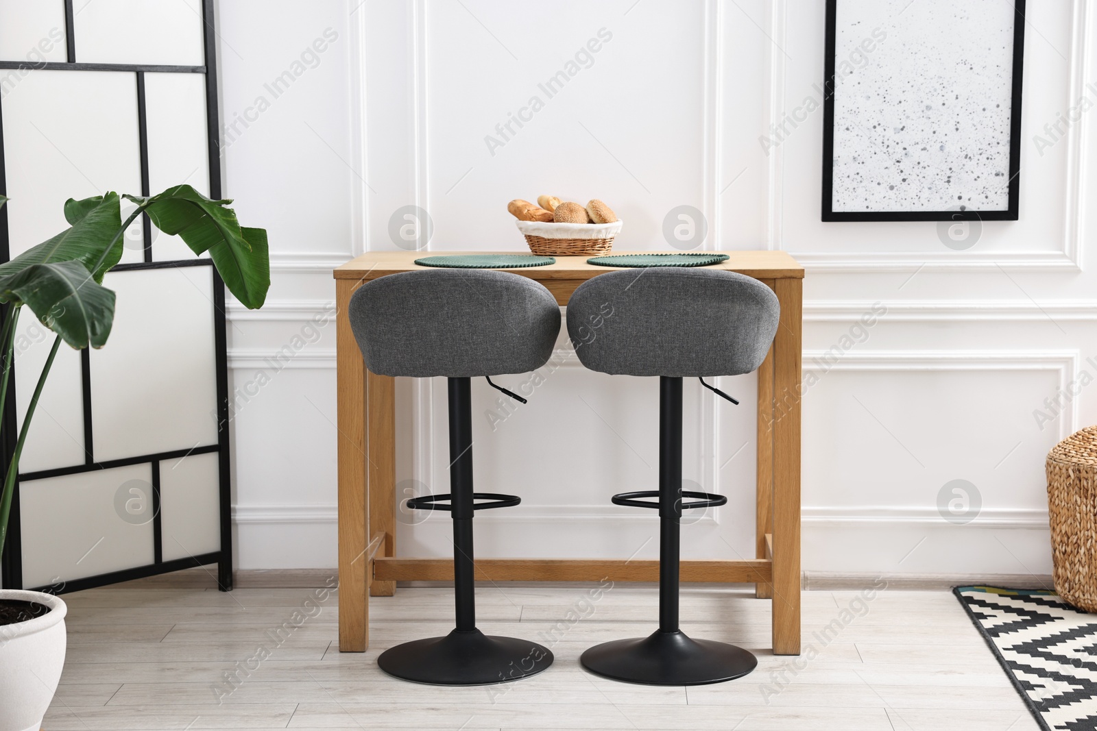 Photo of Bar stools, houseplant and table in stylish room