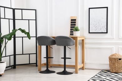 Photo of Bar stools, houseplant and table in stylish room