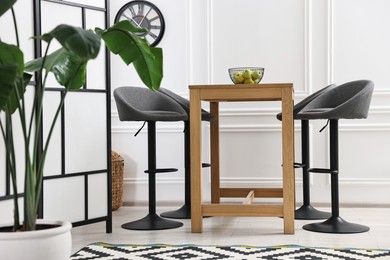 Photo of Bar stools, table, houseplant and folding screen indoors