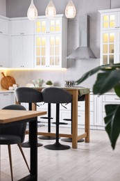 Photo of Bar stools, tables and other furniture in stylish kitchen