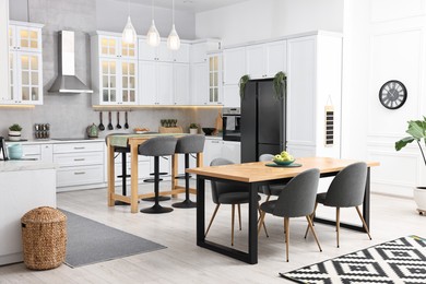 Photo of Bar stools, tables and other furniture in stylish kitchen