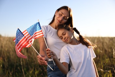 Mother and daughter with flags of USA outdoors, selective focus