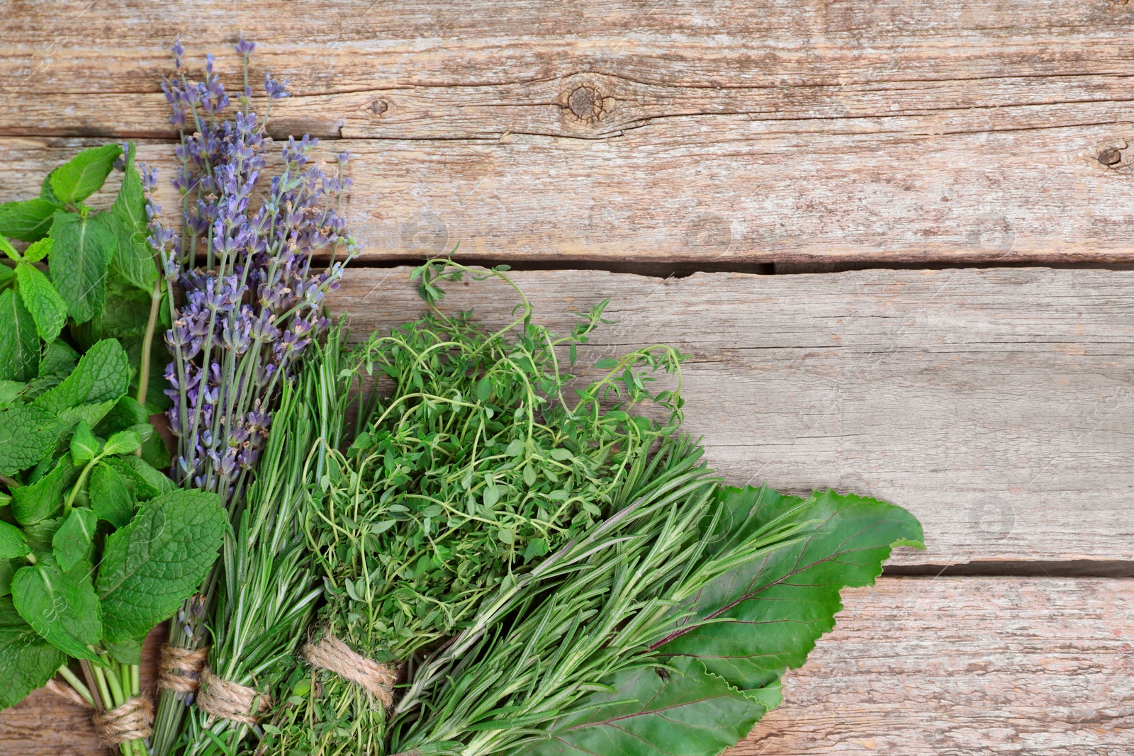 Photo of Different aromatic herbs on wooden table, top view. Space for text