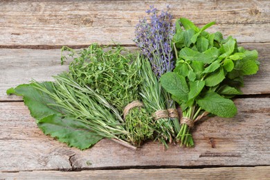 Bunches of different aromatic herbs on wooden table