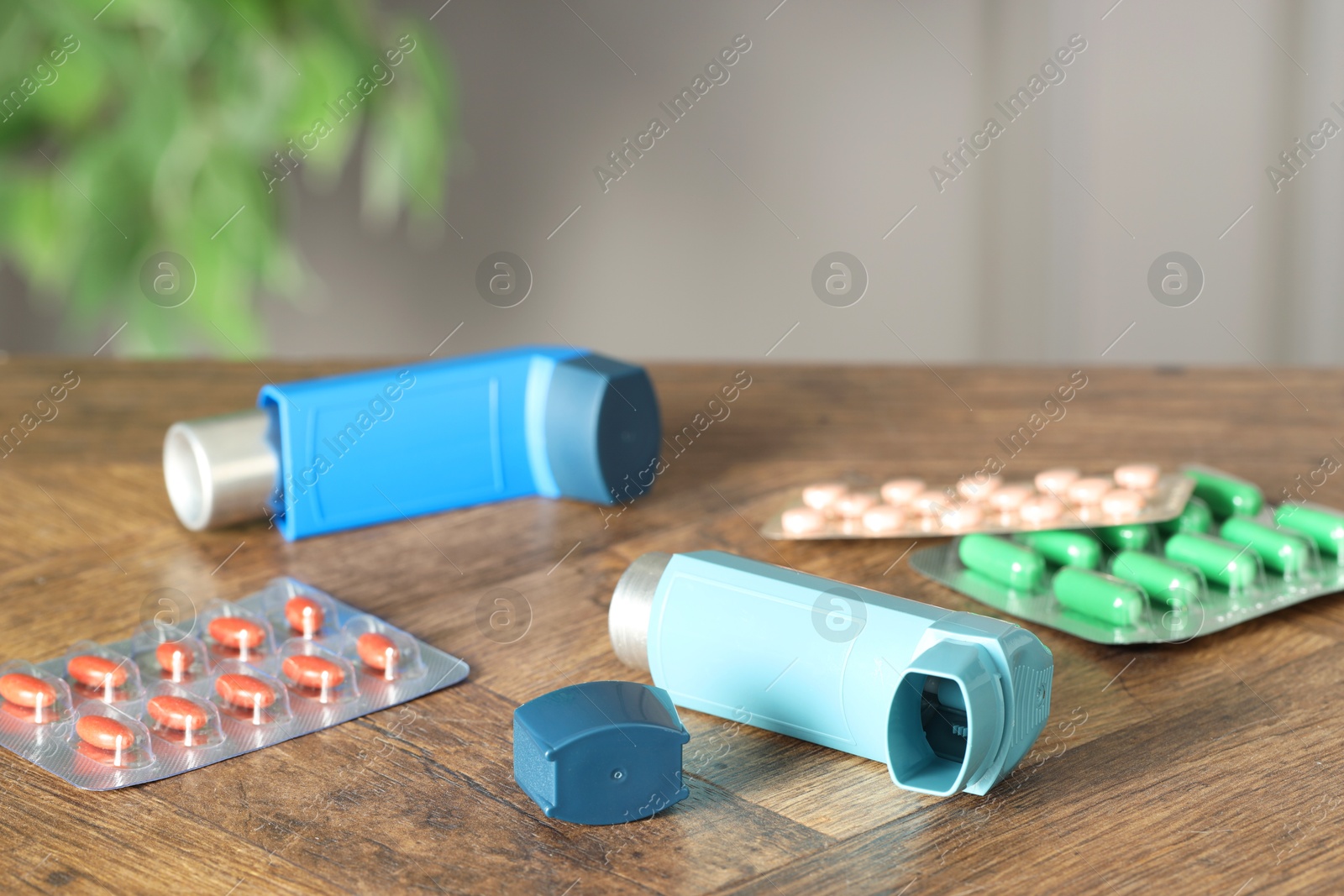 Photo of Inhalers and pills on wooden table indoors, closeup. Asthma treatment