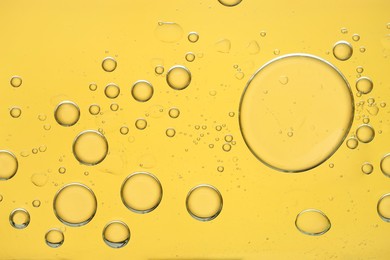 Photo of Sample of cosmetic oil on golden background, macro view