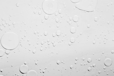 Photo of Sample of cosmetic oil on light grey background, macro view