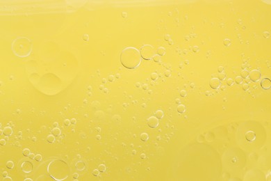 Essential oil bubbles on yellow background, macro view. Cosmetic product