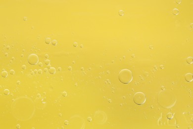 Essential oil bubbles on yellow background, macro view. Cosmetic product