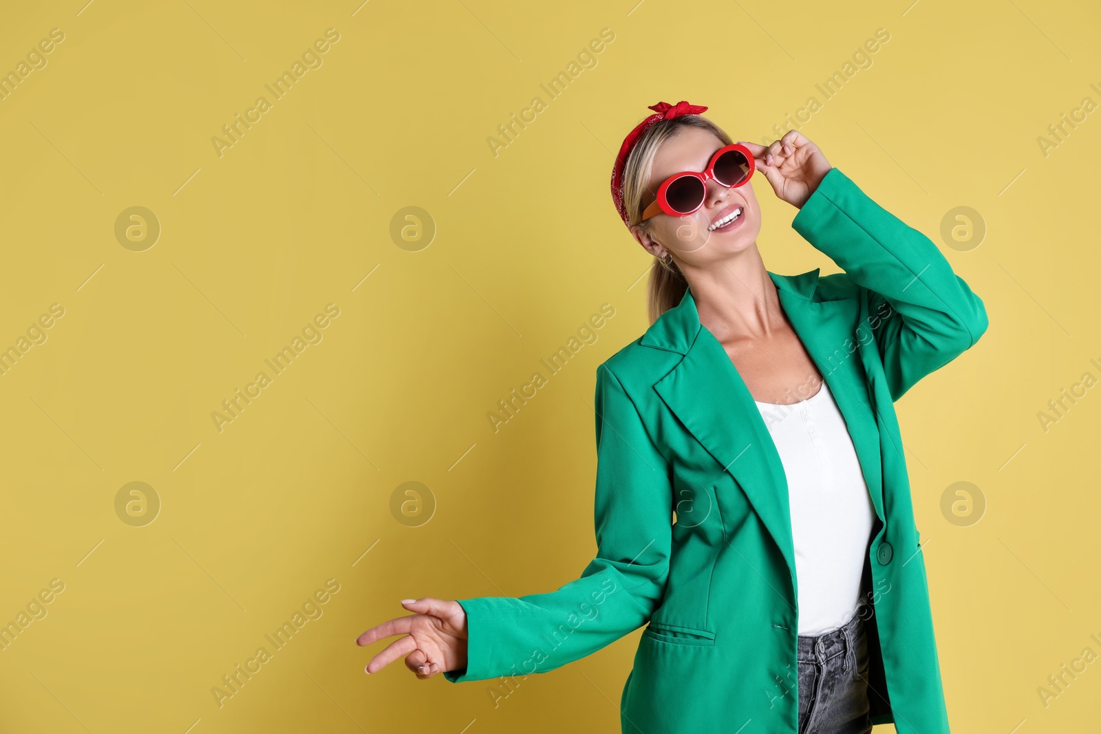 Photo of Beautiful woman in stylish green jacket on yellow background, space for text