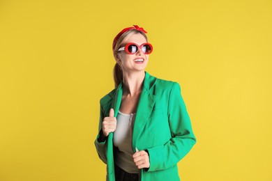 Photo of Beautiful woman in stylish green jacket on yellow background