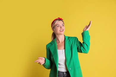 Beautiful woman in stylish green jacket on yellow background