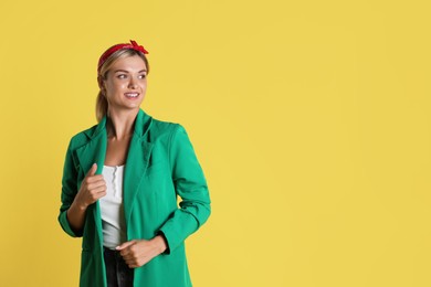 Photo of Beautiful woman in stylish green jacket on yellow background, space for text