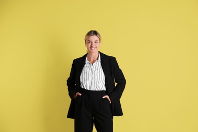 Photo of Beautiful woman in stylish black suit on yellow background