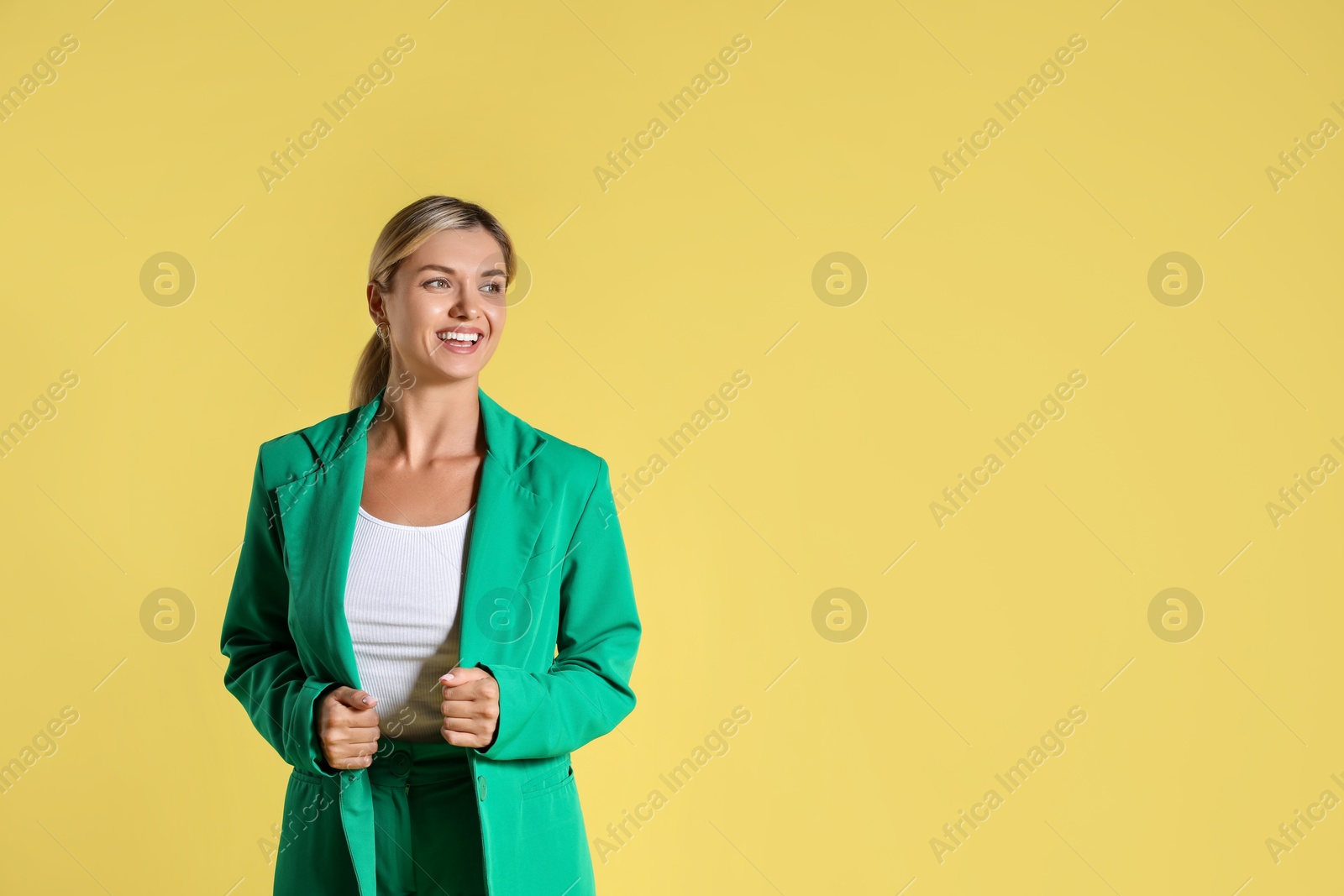 Photo of Beautiful woman in stylish green suit on yellow background, space for text