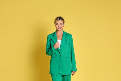 Beautiful woman in stylish green suit on yellow background