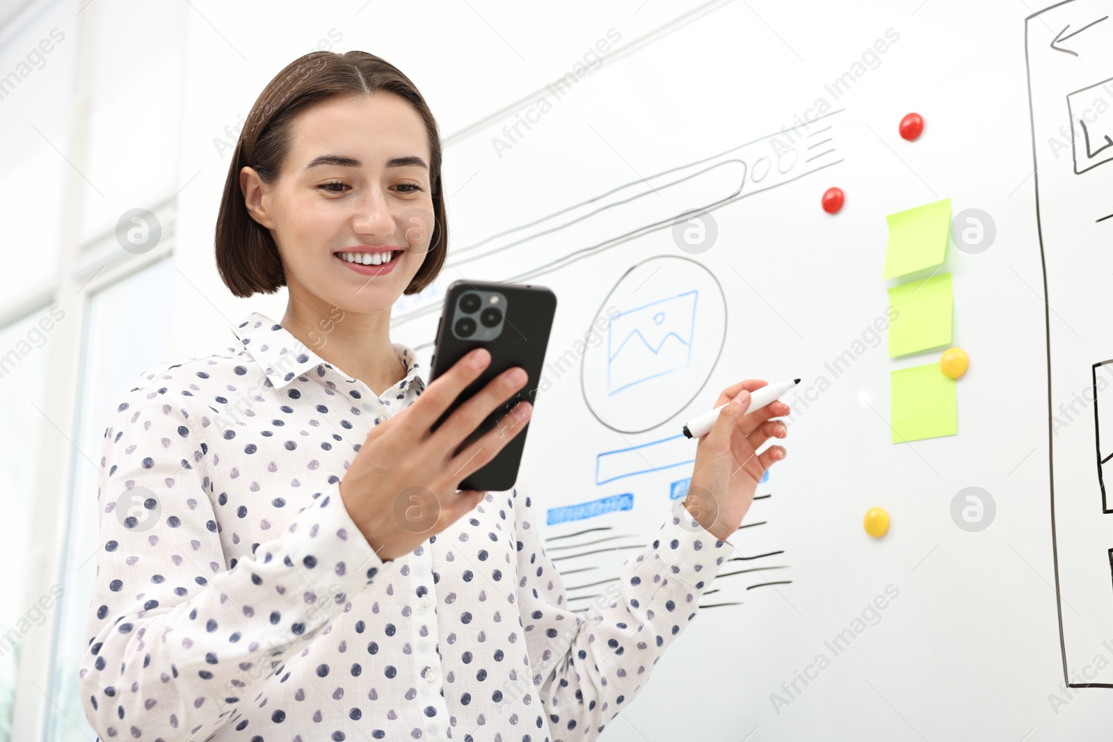 Photo of Developing UI design. Woman drawing website wireframe on whiteboard indoors