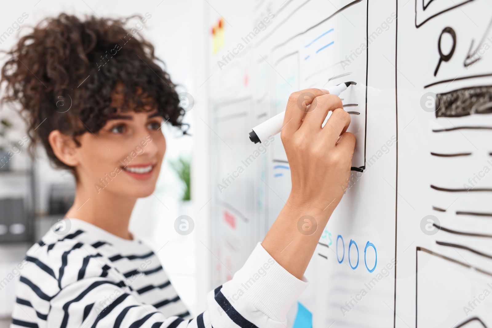 Photo of Developing UI design. Woman drawing website wireframe on whiteboard indoors, selective focus