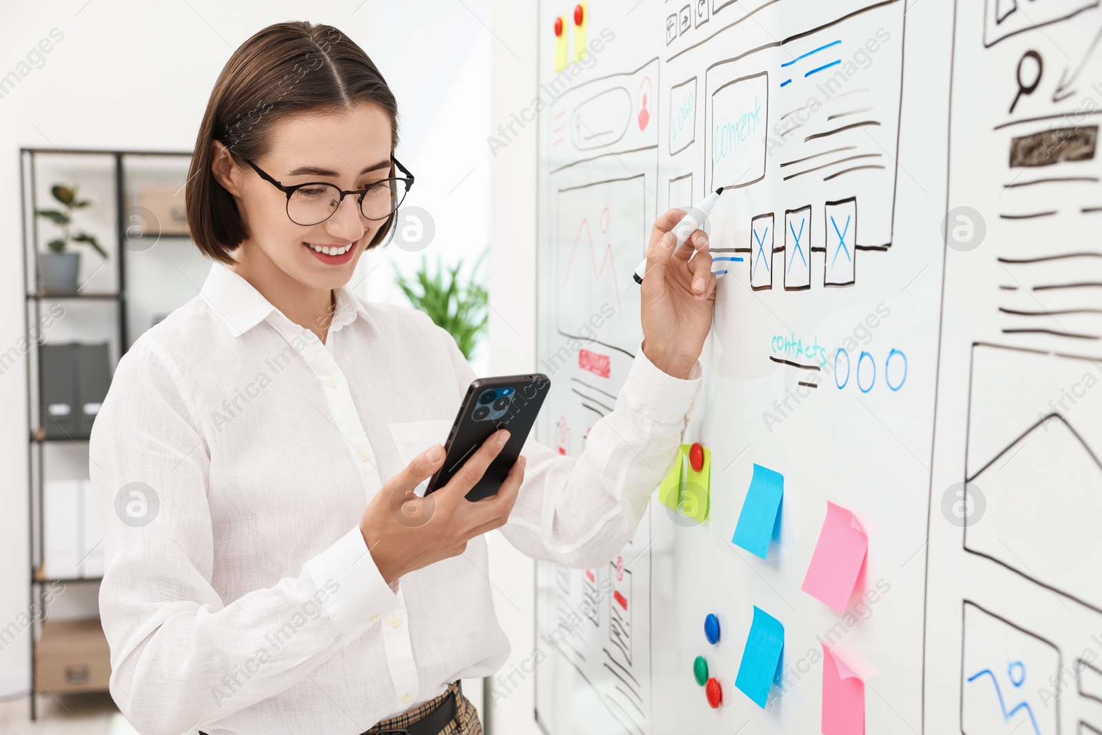 Photo of Developing UI design. Woman drawing website wireframe on whiteboard indoors