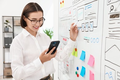 Developing UI design. Woman drawing website wireframe on whiteboard indoors