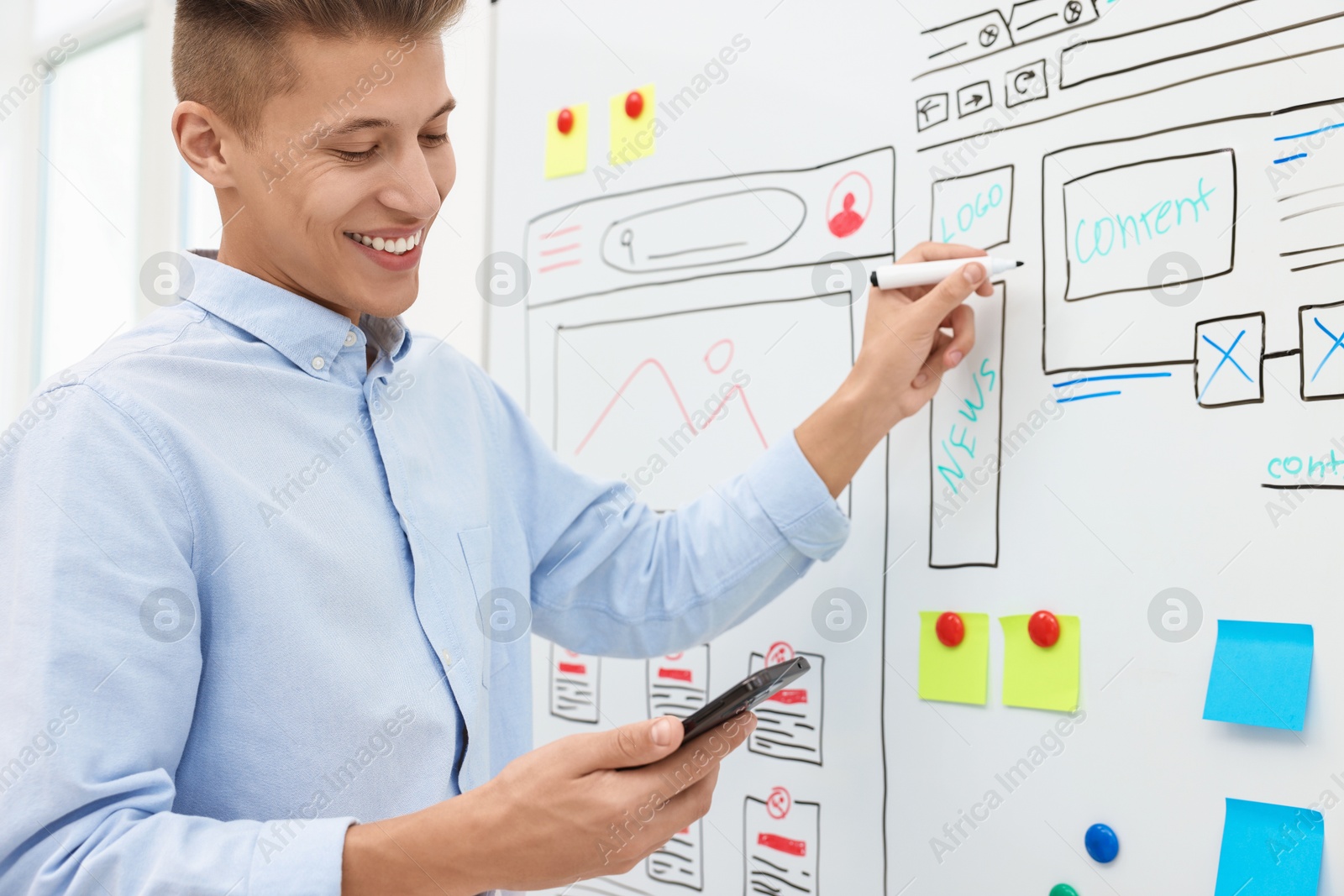 Photo of Developing UI design. Man drawing website wireframe on whiteboard indoors