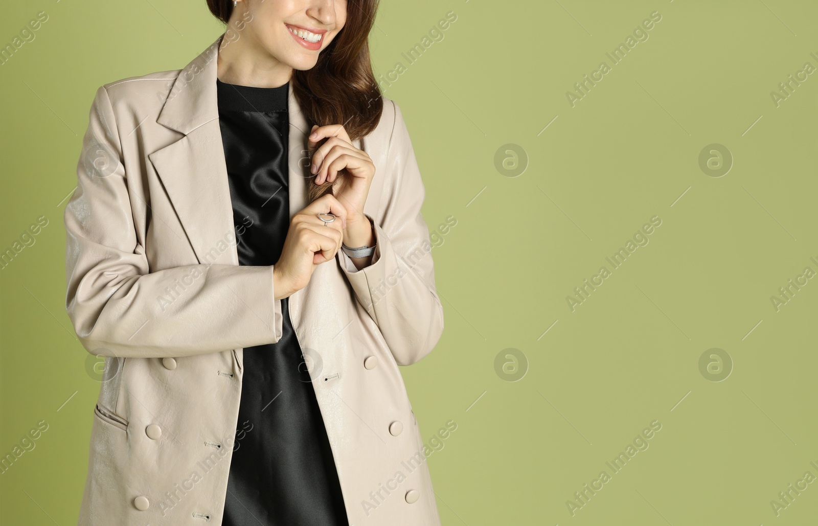 Photo of Beautiful woman in stylish beige jacket on olive background, closeup. Space for text