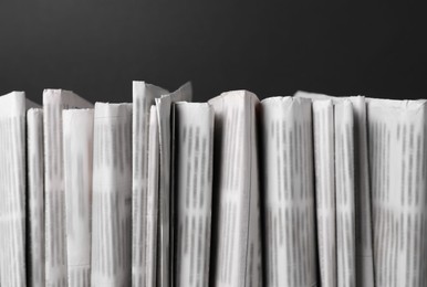 Photo of Many newspapers in different languages on black background, closeup