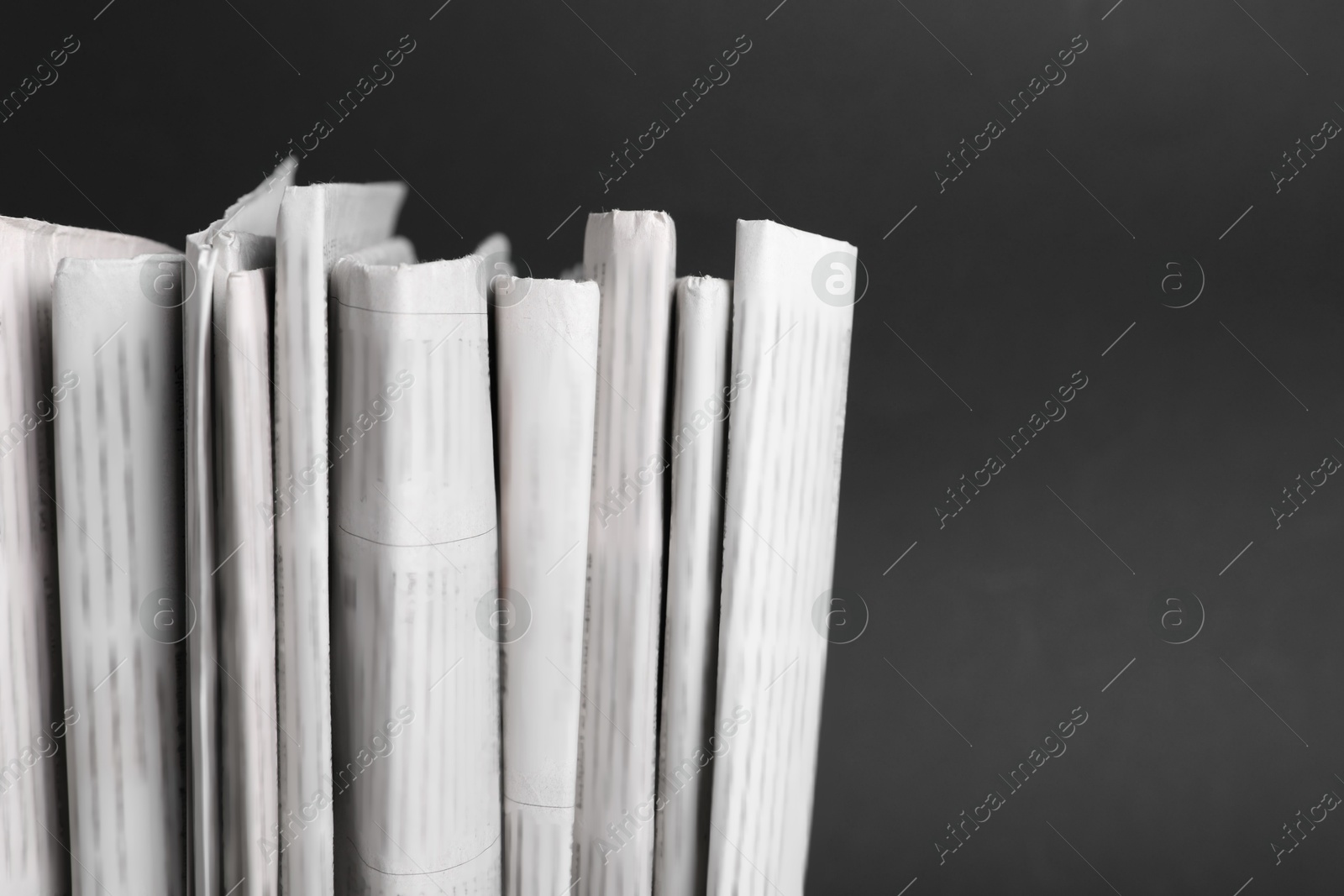 Photo of Many newspapers in different languages on black background, closeup. Space for text