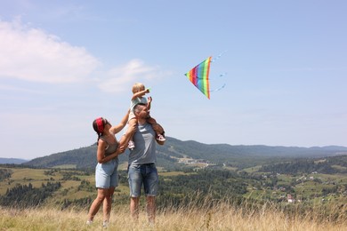 Happy family flying kite at field under blue sky