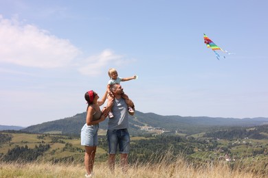 Happy family flying kite at field under blue sky