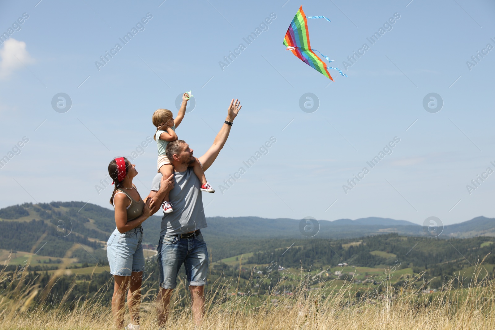 Photo of Family flying kite at field under blue sky