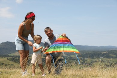 Family checking kite at field under blue sky. Space for text